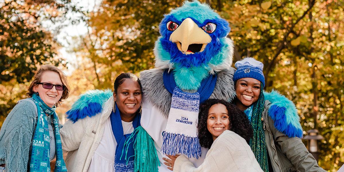 Students with Swoop the Riverhawk on campus in fall
