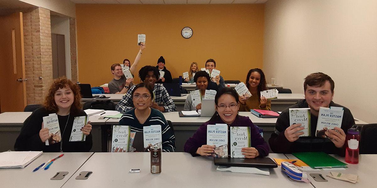 Students in a learning community holding up books